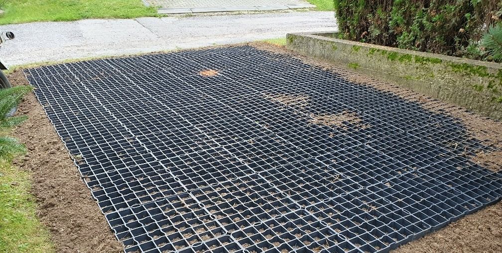 čierny plastový zatrávňovač na parkovacom mieste pri rodinnom dome