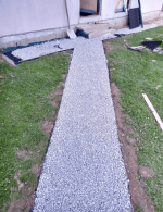 plastový obrubník oddeľujúci štrkovú cestičku s plastového zatrávňovača multigravel od trávnika