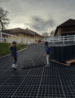 deti ukladajú plastové zatrávňovače na príjazdovej ceste na farmu s koňmi