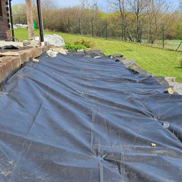 Netkaná agrotextília WIGOFIL 100 g položená na svahu pri rodinnom dome – ochrana proti burine pod štrk, mulč a okrasné záhony