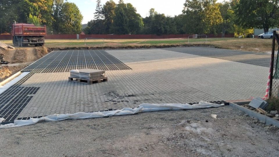 Pokládka sivých plastových zatrávňovačov Hydrogravel PRO na rozsiahlej spevnenej ploche v Kláštore